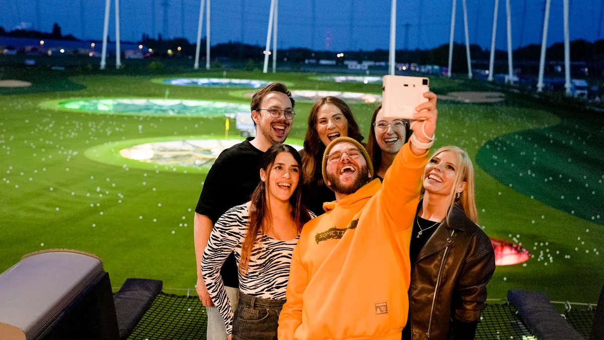 Sechs Freunde machen am Abend ein Selfie in der Bay bei Topgolf