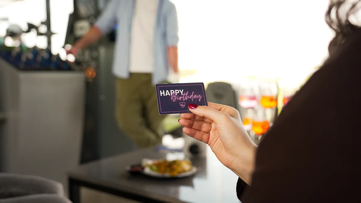 Hand hält eine Topgolf Gutscheinkarte mit der Aufschrift Happy Birthday